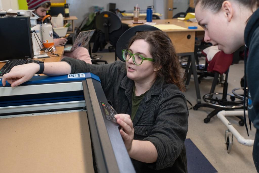 Two students talk over equipment in an assistive technology class